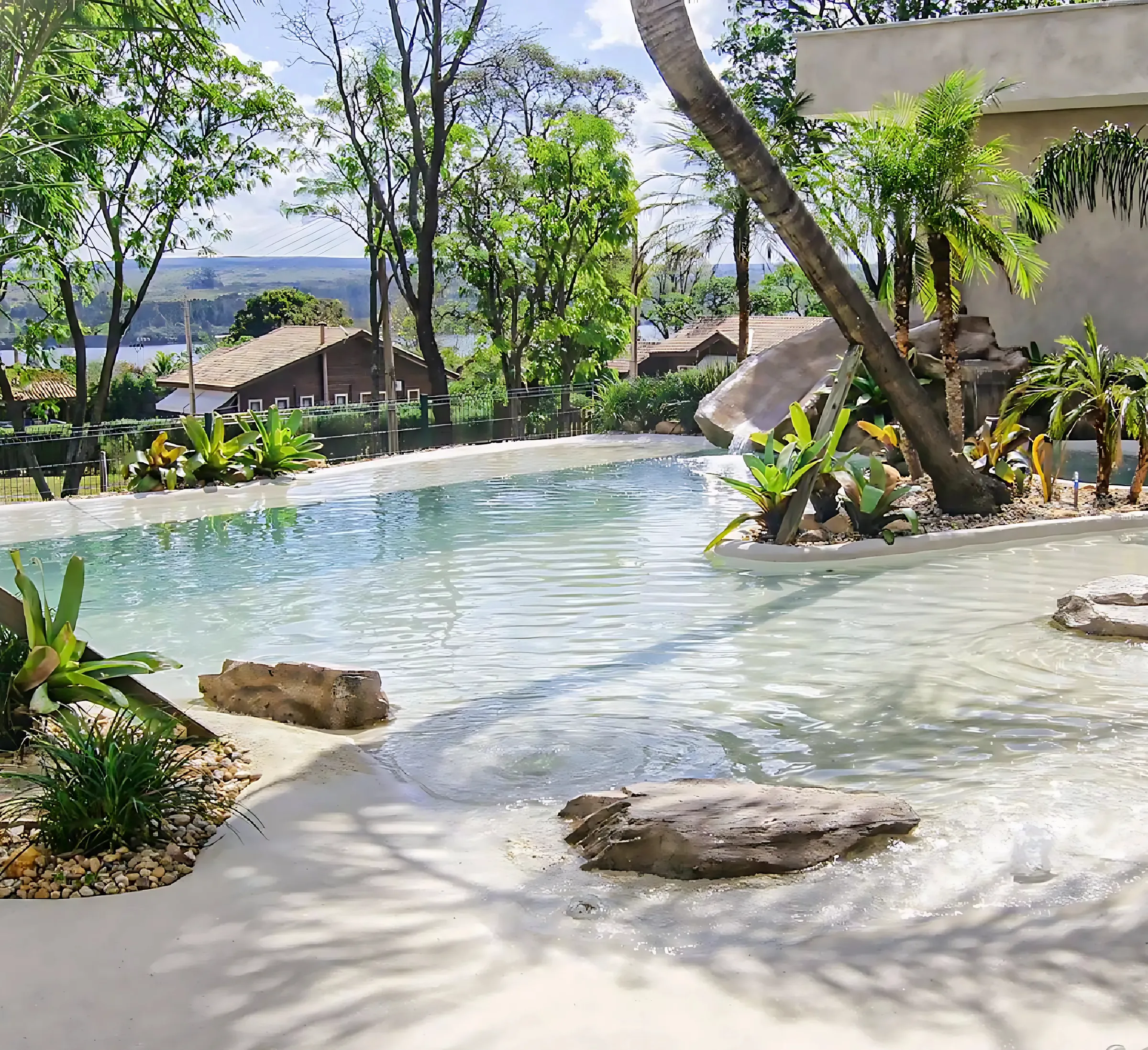 Piscina estilo praia com revestimento monolítico claro